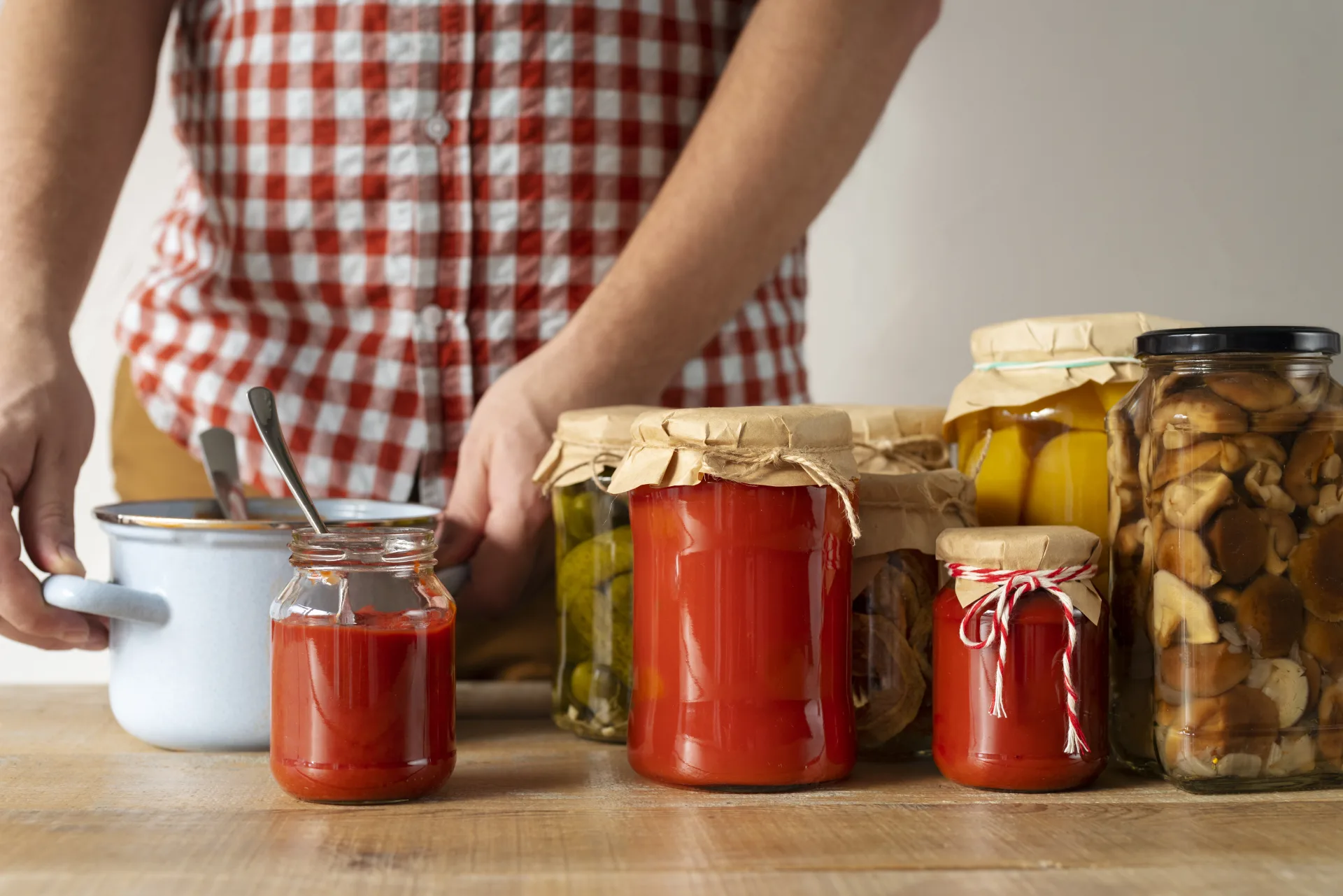 Barattoli di conserve fatte in casa — passata di pomodoro, cetriolini, limoni e funghi — su un tavolo di legno