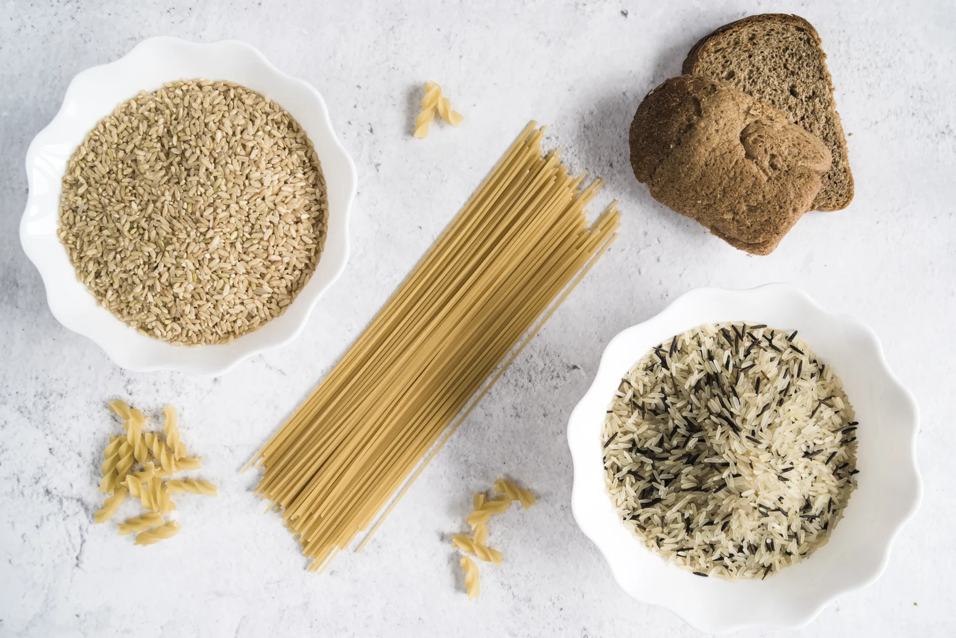 Riso integrale, riso bianco con riso selvatico, spaghetti, fusilli e pane integrale visti dall'alto
