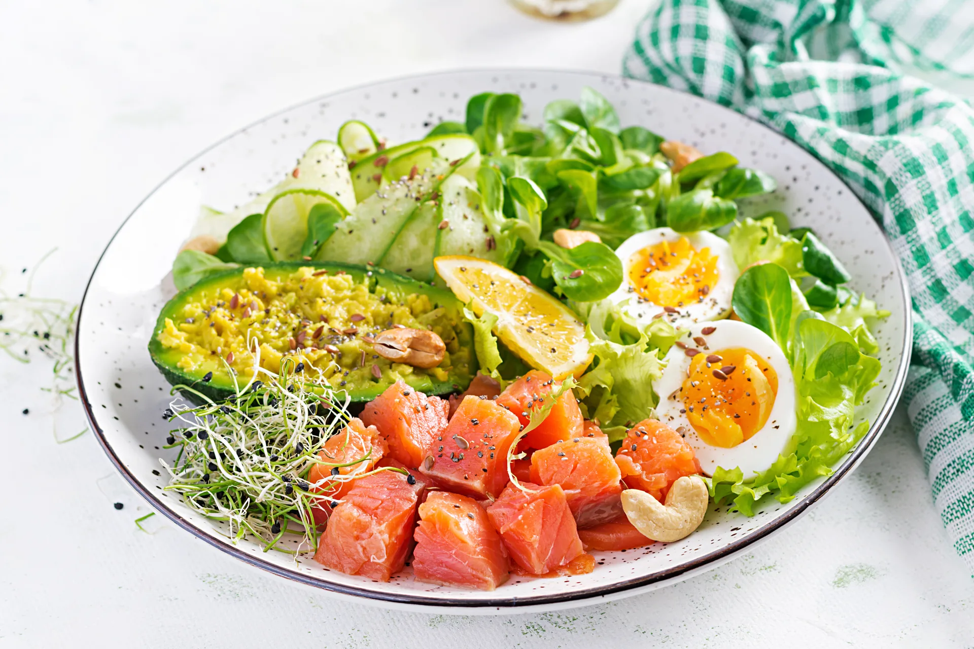 Un piatto di salmone a cubetti con avocado, uova sode, cetriolo e insalata